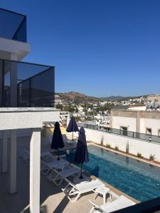 a swimming pool with chairs and umbrellas on a building at Lumy Suite Hotel Bodrum Gumbet - Private Pool in Bodrum City