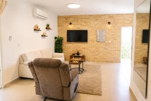 a living room with a couch and a chair at סוויטת אריאל - סוויטה משפחתית עם מרפסת בבית שאן in Bet Sheʼan