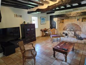 a living room with a table and a stone fireplace at La Maraiquaise in Marais-Vernier