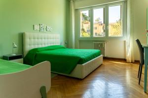a bedroom with a green bed and two windows at San Felice Central Room in Bologna