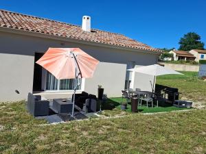 a patio with two umbrellas and a table and chairs at Maison individuelle 6 personnes in Coux