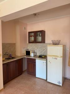 a kitchen with a white refrigerator and wooden cabinets at Dream Bay Apartments in Tsarevo