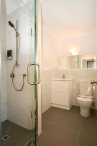 a white bathroom with a shower and a toilet at Dukes Midway Lodge in Auckland +26 photos