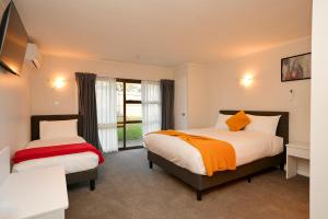 a bedroom with two beds and a window at Dukes Midway Lodge in Auckland