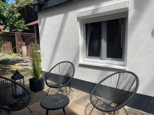 a patio with three chairs and a table and a window at Garten Oase Weisweil in Weisweil