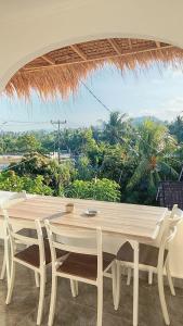 a table and chairs in front of a large window at USTIN Villas Lombok in Bumbang