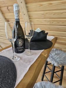 a bottle of wine and two glasses on a table at Casuța din Colți in Colţi