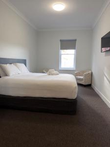 a white bedroom with a bed and a window at Queens Head Hotel in West Hobart