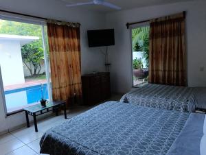 a bedroom with two beds and a television and a window at Chinelos Ixtapa in Ixtapa