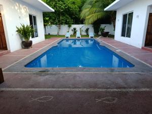 a blue swimming pool with two chairs and a house at Chinelos Ixtapa in Ixtapa