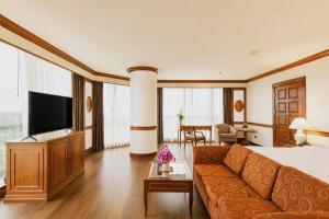 a hotel room with a couch and a television at The Twin Lotus Hotel in Nakhon Si Thammarat