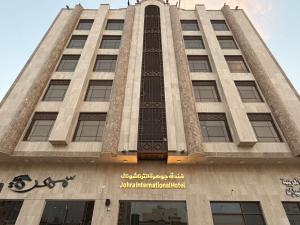 a tall building with a sign in front of it at Johra International Hotel فندق جوهرة إنتر ناشونال in Medina