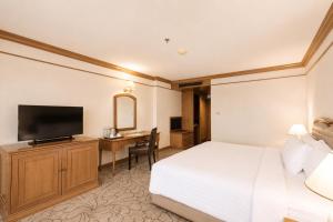 a hotel room with a bed and a desk with a television at The Twin Lotus Hotel in Nakhon Si Thammarat +28 photos