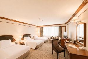 a hotel room with two beds and a desk at The Twin Lotus Hotel in Nakhon Si Thammarat