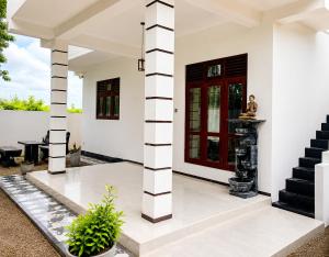 a white house with a red door and stairs at Blue Waves Ocean Mirissa in Mirissa