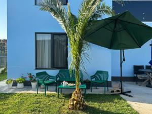 a palm tree sitting next to two chairs and an umbrella at Sunset paradise in Ureki