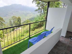 a balcony with two blue chairs and a view at Rosenka haputhale in Haputale