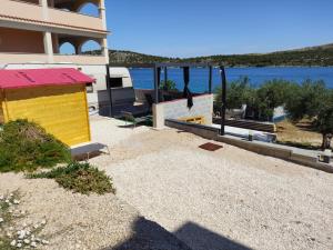a building with a yellow and red roof next to the water at Caravan with private toilet and kitchen 2 in Grebaštica