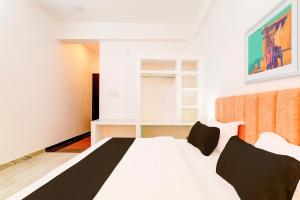 a bedroom with a white bed with black pillows at Hotel O Samar palace in Lucknow +21 photos
