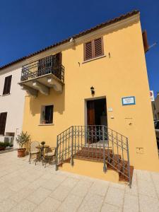 a yellow building with a balcony and a table and chairs at Casa Giulia in Palau