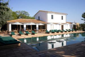 a pool with chairs and umbrellas next to a building at Resort & Glamping Terre di Sacra in Toscana in Capalbio