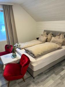 a bedroom with a bed and a red chair at Mentebauer Traudi's Ferienhof in Rothenthurn