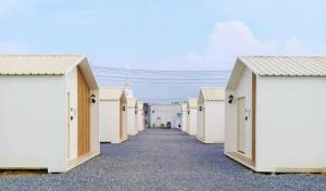 a row of white beach huts on a gravel road at บ้านตัวเล็กศาลายา in Sathani Wat Suwan