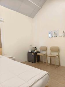 a white room with two chairs and a bed at บ้านตัวเล็กศาลายา in Sathani Wat Suwan