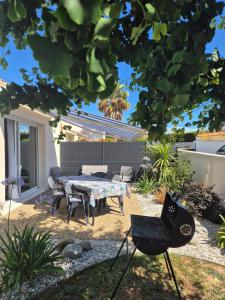 a backyard with a table and chairs and a grill at Chez Carisa in Puilboreau