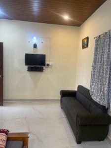 a living room with a couch and a flat screen tv at Skyview homestay Devaramane in Mudigere