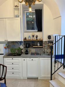 a kitchen with white cabinets and a sink at Circumpiso in Massa Lubrense