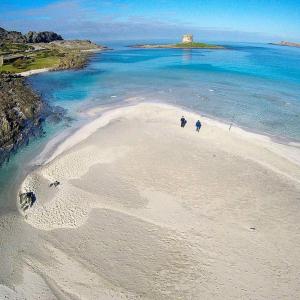 two people walking on a beach in the ocean at Near The Sea in Bosa Marina