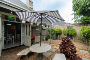 a patio with a table and benches and an umbrella at Crown Oak in Gqeberha