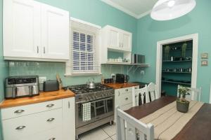 a kitchen with white cabinets and a table and a stove at Crown Oak in Gqeberha