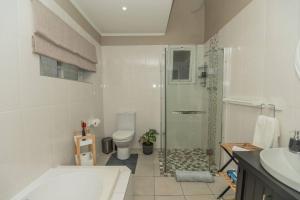 a bathroom with a shower and a toilet and a sink at Crown Oak in Gqeberha +44 photos