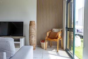 a living room with a tv and a chair at Paul Sun Scape - Seaside Ocean & Sunset View in Paul do Mar