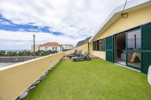 a balcony with chairs and grass on a building at Paul Sun Scape - Seaside Ocean & Sunset View in Paul do Mar