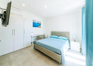 a white bedroom with a bed and a desk at Villetta Mami in Ischia