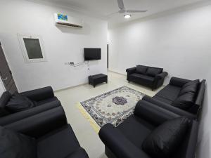 a living room with two black couches and a tv at رحاب السعاده rehab alsaadah apartment in Salalah