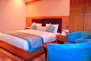 a bedroom with a bed and two blue chairs at Hotel Landmark Near Golden Temple in Amritsar