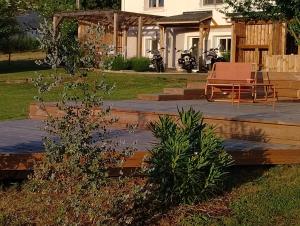 a deck with a bench and a table in a yard at L'atelier in Sugères