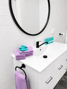 a white bathroom with purple towels and a mirror at Chelsea Motor Inn in Coffs Harbour