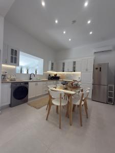 a white kitchen with a table and chairs in it at Katsaras Sunset & Pool House in Kremasti