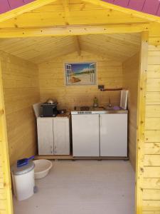 a small kitchen in a wooden cabin with a sink at Caravan with private toilet and kitchen 2 in Grebaštica +14 photos