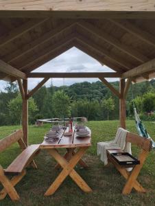 a wooden picnic table under a pavilion in a field at Domek Kaprys Piatkowa in Piątkowa