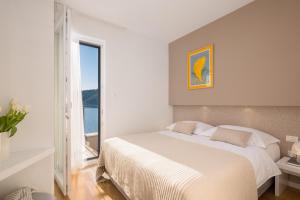 a white bedroom with a large bed and a window at Villa Lavanda Deluxe in Rogoznica