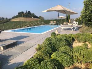a swimming pool with an umbrella and a table and chairs at Casa Molisso in Montegrosso dʼAsti