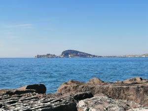 a large body of water with rocks in the foreground at Happy Rock in Formia