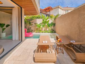 a patio with a table and chairs and a pool at Antonella De Rosa Villas in Nusa Dua