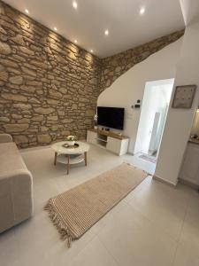 a living room with a couch and a stone wall at Katsaras Sunset & Pool House in Kremasti